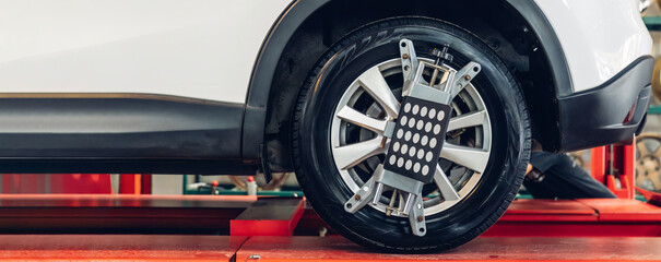 Car wheel centering machine adjustment. Auto service mechanic installing wheel alignment sensor on tire during vehicle suspension alignment adjustment