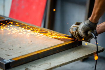 Grinding machine at work. Sparks fly from under the grinders, men's work. Dark background with copy space.