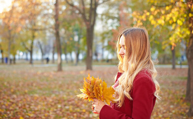 A woman in a red coat and a black skirt walks in an autumn park. The concept of autumn and the beauty of nature.