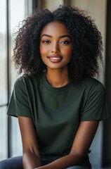 Fototapeta premium A army green t-shirt, worn by an African American woman model posing for brand photoshoots in her studio. The T-shirt is loose-fitting, she has curly hair and sits cross-legged wearing high heels.
