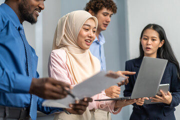 Diverse group of business professionals in formal collaborating during a corporate meeting, focused on technology and teamwork, asian businesswoman leading with laptop, teamwork and collaboration