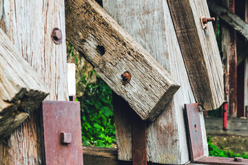 The ancient railway piers and large beams made of wood support an old rundown train bridge and were constructed during World War II.  View of old wooden bridge of train railway along cliffs and rivers