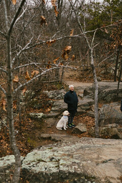 Older man in fall forest with his golden doodle dog on hike