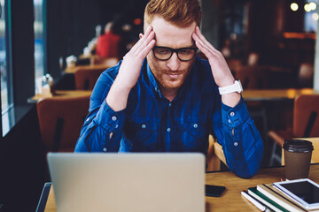 Disappointed caucasian male freelancer received email with bad news from work feeling unhappy from deadline in coworking space, puzzled man thinking about ideas for solving problem with antivirus app