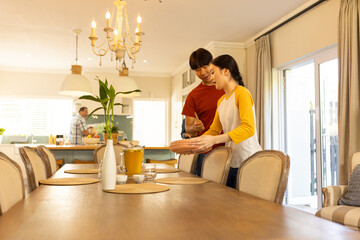 Setting table for family meal, young asian brother and sister arranging dishes in dining room