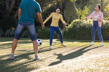 Playing soccer outdoors, asian family enjoying time together on sunny day