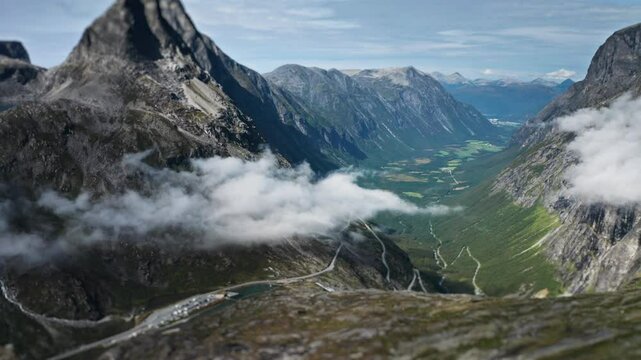 Trollstigen zigzagging road framed by mountains and a flowing river, creating a dramatic and scenic view.