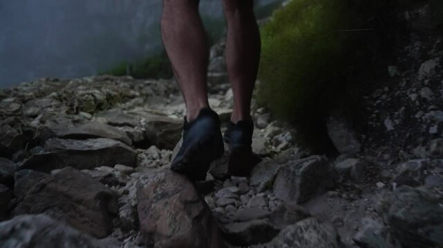 A close up of an athletic mans calves running across rocky terrain on a trail run in the darkness of the evening