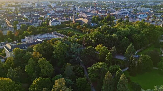 Smooth aerial movement above the Parc du Thabor's parkside with Thabor church, Rennes, France.