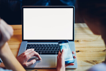 Cropped image of male and female hands using technology for communication online, man searching information on website via laptop computer with blank screen area for your internet advertising