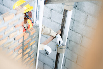 An engineer holding a tape measure inspects the building construction standards to ensure that every part of the structure complies with regulations and is safe for future use.
