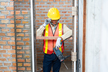 A construction worker stands holding a drill at the construction site, skill and the tools essential for building projects.