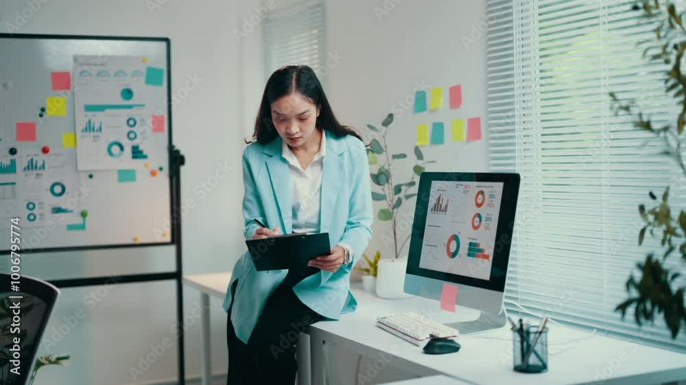 Poster businesswoman is standing at her desk, analyzing data on a clipboard and her desktop computer. she i