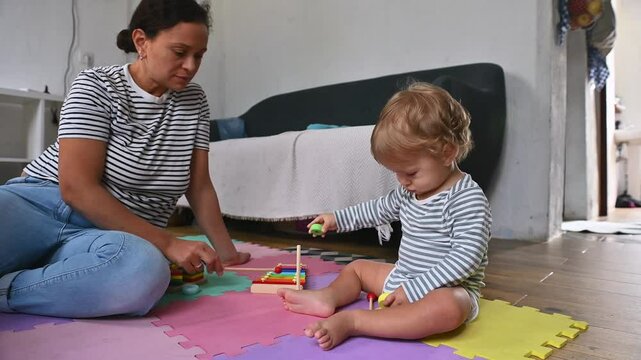 Mother and toddler playing together on colorful playmat in cozy home setting, fostering early development and bonding