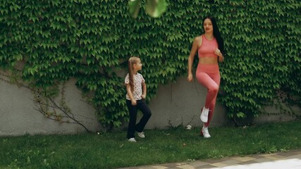 Mother and daughter outdoor workout in lush backyard during sunny afternoon