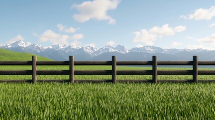 Fototapeta premium Wooden fence in a green field with mountains and blue sky in the background.