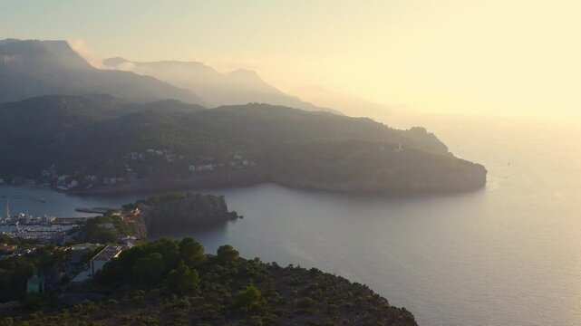 Aerial view of evening town of Port de Soller. Yacht and boat bobbing on water, flooded with sunset light. Around mountain, the waterfront. Mallorca. Spain