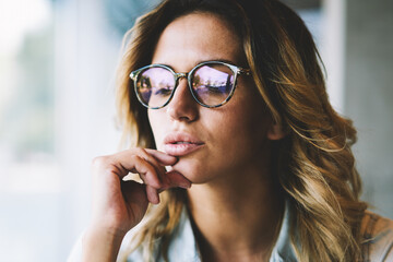 Clever pondering hipster girl in optical spectacles for provide eyes protection feeling confused on information during leisure time, caucasian contemplative woman in eyewear thinking about ideas