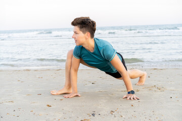 Sporty woman is engaged in animal flow gymnastics outdoors on sea beach. Female trains with Animal...