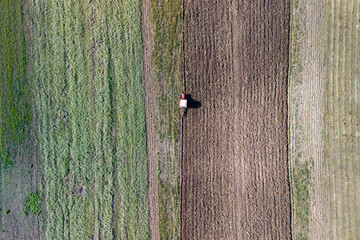 Fototapeta premium Aerial view of a tractor working in a field, showcasing differing soil textures and patterns, emphasizing agricultural productivity.