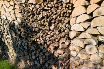 A pile of firewood stacked neatly outdoors, showcasing various log cuts and textures in a natural setting. Ideal for nature and home-related themes.