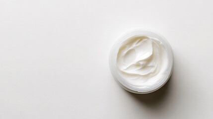 Close-up top view of a moisturizer sample in a jar. Shiny, smooth cream texture without any branding or logo. Clean, simple white background.