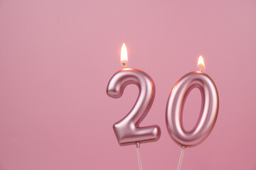 Burning pink birthday candles on pink background, number 20