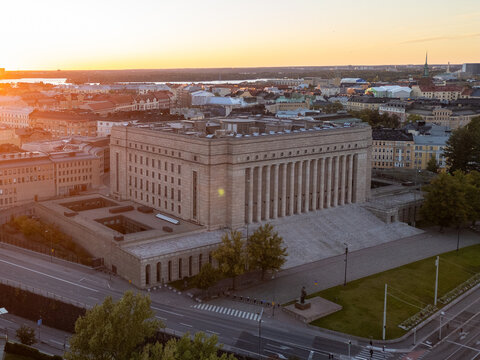 Cityscape of Helsinki's T&ouml;&ouml;l&ouml; district, showcasing residential streets and buildings during a summer evening at sunset, with a view of the Finnish Parliament in the background