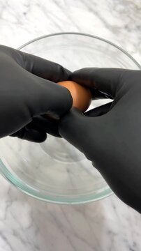 Breaking fresh eggs into a glass recipient for food preparation