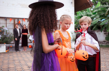 Obraz premium Children in ghost costumes are having fun trick-or-treating on Halloween