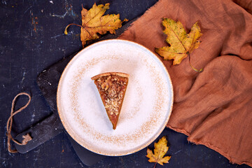 Homemade pumpkin spice pie for the Thanksgiving holiday. Top view with dark background with maple leaves