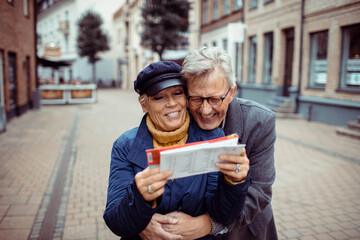 Senior couple laughing and exploring city with a map