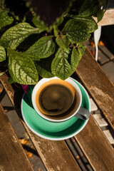 Close-up of a cup of black coffee in the sunlight on wooden table