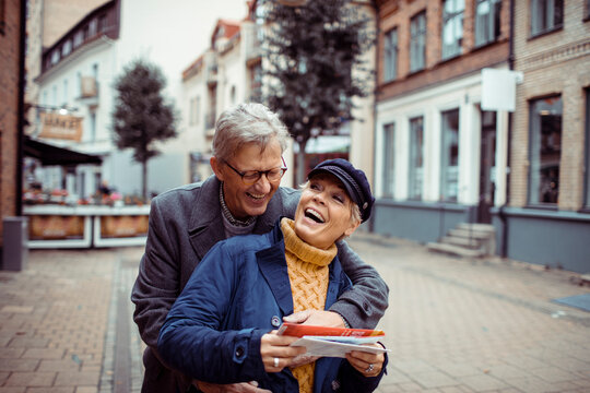 Senior couple laughing and exploring city with a map