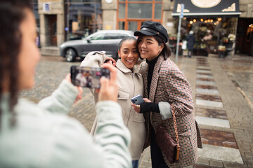 Friends posing for a street photo being taken with a smartphone