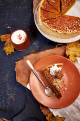 pumpkin pie on a dark background on a terra cotta plate. Top view