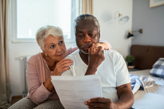 Elderly interracial couple reviewing financial documents together - Powered by Adobe