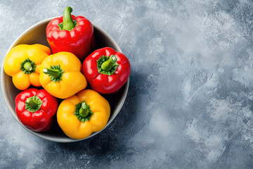 Colorful bell peppers in a bowl on a grey background, top view with copy space for text or design 