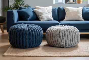 Two knitted poufs near dark blue corner sofa. Scandinavian home interior design of modern living room.