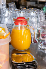 Jugs of orange juice, rows of empty glasses on a buffet table. Holidays, celebrations and events. Close-up.