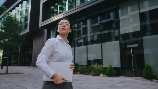 Asian businesswoman checks time on watch hurrying to office