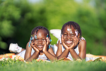 Carefree Laughter: Sisters Enjoying a Sunny Day on the Grass