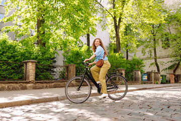 Naklejka premium Happy woman riding bicycle at the city street outdoor. Freedom on two wheels. Active lifestyle.