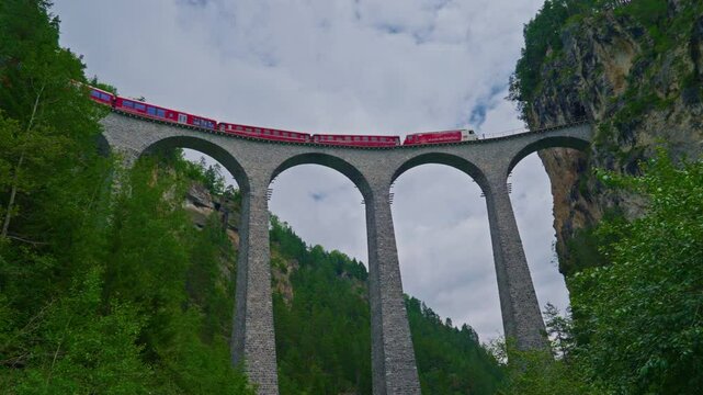 The Red Express Train passes the world famous Landwasser Viaduct in Switzerland in summer