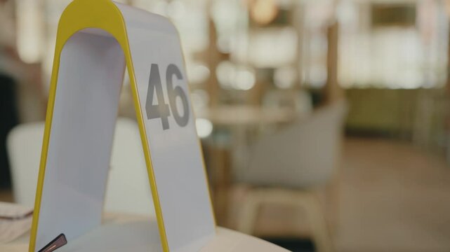 Close-up of table number 46 in a contemporary restaurant. The background is blurred, highlighting the table number. Closeup on table stand with number in cafe