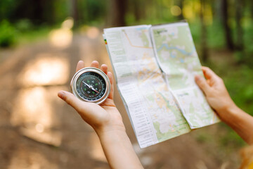 Traveler young woman searching direction with a compass on background of map in the forest. Adventure, vacation concept. Active lifestyle © maxbelchenko