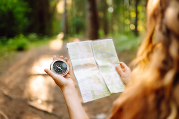 Traveler young woman searching direction with a compass on background of map in the forest....