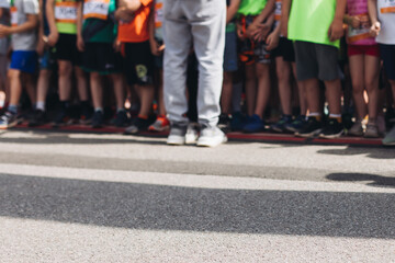 Children marathon runners crowd, young teen sportsmen participants start running in the city streets, crowd of kids joggers in motion, kid group athletes outdoor run, family competition in summer day