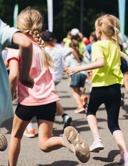 Fototapeta premium Children marathon runners crowd, young teen sportsmen participants start running in the city streets, crowd of kids joggers in motion, kid group athletes outdoor run, family competition in summer day