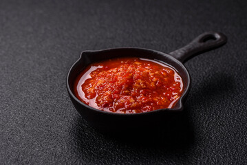 Delicious hot spicy red sauce with salt and spices in a ceramic bowl
